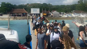 Passengers queuing in an orderly line to board a fast boat at Buyuk Harbor, organized boarding system in Nusa Penida.
