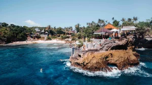 Adventurous tourist cliff jumping at the famous Blue Lagoon or Secret Point in Nusa Ceningan, iconic activity for thrill-seekers.