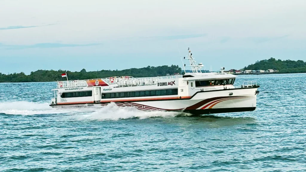 Dcamel Fast Boat cruising at high speed from Bali to the Gili Islands, modern fast boat exterior on blue ocean.