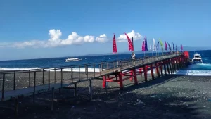 Sturdy iron and wood construction of the dock at Kusamba Harbor, robust and practical infrastructure for boat transfers.