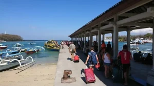 Passengers walking on the dock towards their fast boat at Padang Bai fast boat harbor, bustling main port for Bali to Lombok and Gili Islands transfers.