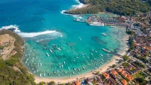 Aerial or elevated view of Padang Bai Harbor Bali, showing the layout of jetties, ferries, and surrounding hills.
