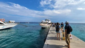 Passengers boarding a fast boat via the floating jetty at Toyapakeh Harbor, typical embarkation process in Nusa Penida.